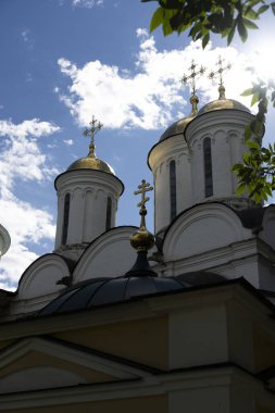 Mavi gökyüzüne karşı altın kubbeleri olan eski beyaz taş binalar.