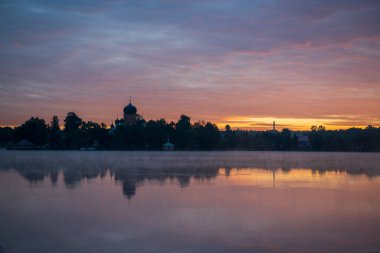 Gün doğumunda gölün ortasındaki antik ada manastırı.