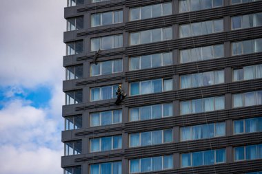 Bir endüstriyel tırmanıcı yüksek bir duvarda, pencereleri yükseklerde çalışır.