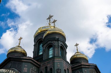 Koyu renkli bir tapınağın panoramik görüntüsü. Gri bulutların arka planında altın kubbeler.