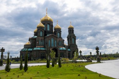 Koyu renkli bir tapınağın panoramik görüntüsü. Gri bulutların arka planında altın kubbeler.
