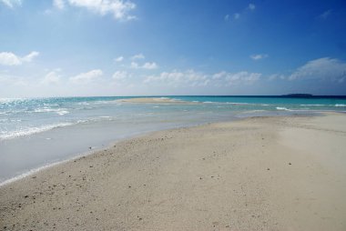 Mavi gökyüzüne karşı turkuaz suyu olan kar beyazı bir ada.