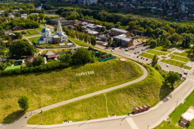 Yazın eski bir kilisenin panoramik manzarası yeşil bir tepede bulutlu bir arka planda