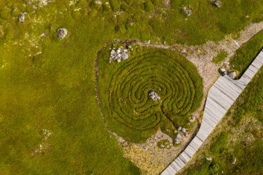 Issız bir adanın panoramik görüntüsü. Eski bir kilise ve insansız hava aracından çekilen antik taş labirentler.
