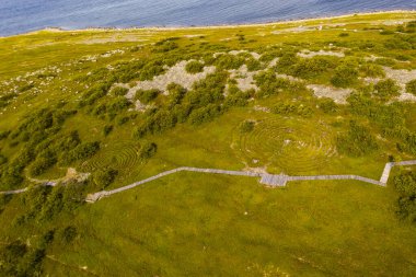 Issız bir adanın panoramik görüntüsü. Eski bir kilise ve insansız hava aracından çekilen antik taş labirentler.