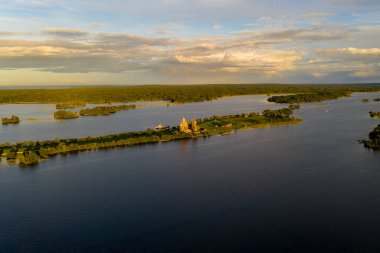 Gölün panoramik manzarası. Birinde bir sürü ada var. Gün batımında ahşaptan yapılmış eski bir tapınak var.