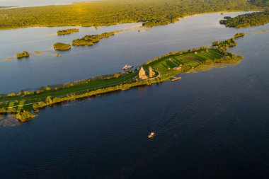 Gölün panoramik manzarası. Birinde bir sürü ada var. Gün batımında ahşaptan yapılmış eski bir tapınak var.