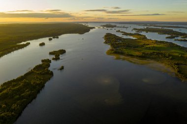 Gölün panoramik manzarası. Birinde bir sürü ada var. Gün batımında ahşaptan yapılmış eski bir tapınak var.