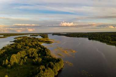 Gölün panoramik manzarası. Birinde bir sürü ada var. Gün batımında ahşaptan yapılmış eski bir tapınak var.