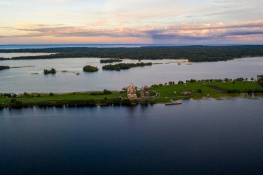 Gölün panoramik manzarası. Birinde bir sürü ada var. Gün batımında ahşaptan yapılmış eski bir tapınak var.