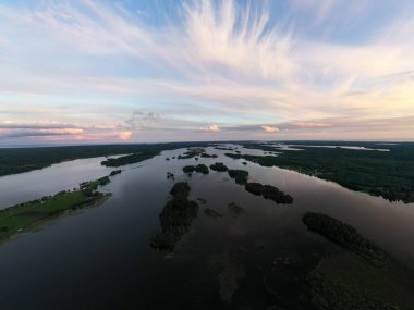 Gölün panoramik manzarası. Birinde bir sürü ada var. Gün batımında ahşaptan yapılmış eski bir tapınak var.