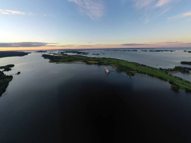 Gölün panoramik manzarası. Birinde bir sürü ada var. Gün batımında ahşaptan yapılmış eski bir tapınak var.