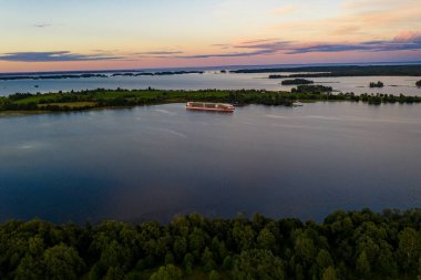 Gölün panoramik manzarası. Birinde bir sürü ada var. Gün batımında ahşaptan yapılmış eski bir tapınak var.