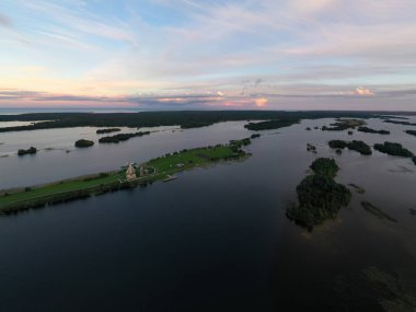 Gölün panoramik manzarası. Birinde ahşaptan yapılmış antik bir tapınak var.