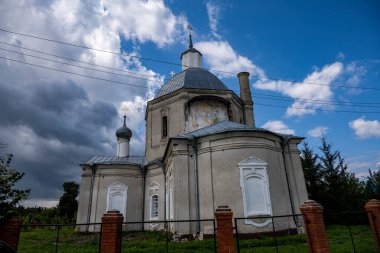Mavi gökyüzüne karşı yeşil ağaçların arasında eski bir malikanenin kalıntıları.