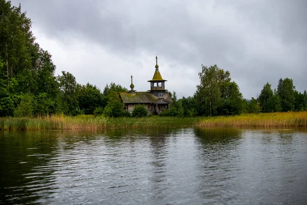 old wooden church on the island between trees in the rain