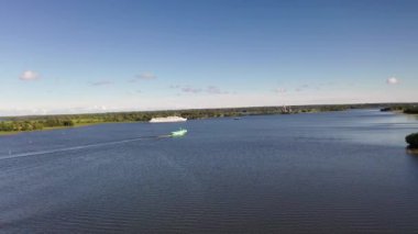 Göl üzerindeki yeşil adaların panoramik bir görüntüsü. Eski mimari yapıları olan gemiler insansız hava aracından çekiliyor.
