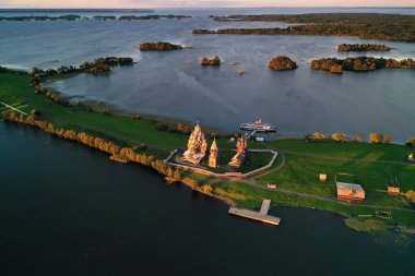 Göl kenarındaki eski ahşap binalarla adanın panoramik görüntüsü insansız hava aracından çekiliyor.
