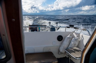 Mavi suların ve mavi gökyüzünün arka planında yüksek süratli bir teknenin yanından geçen gemilerin bulunduğu adalar.