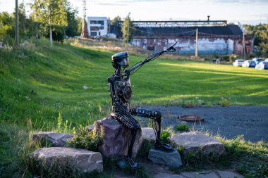 Gölün kenarındaki setin yanında dinlenen insanlar, olağandışı anıtlar ve sürekli var olan kuşlar var.