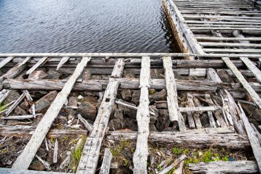 Güneşin doğuşunda eski ahşap liman, taş ve deniz manzarası