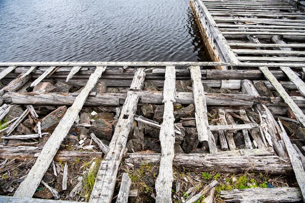 Güneşin doğuşunda eski ahşap liman, taş ve deniz manzarası