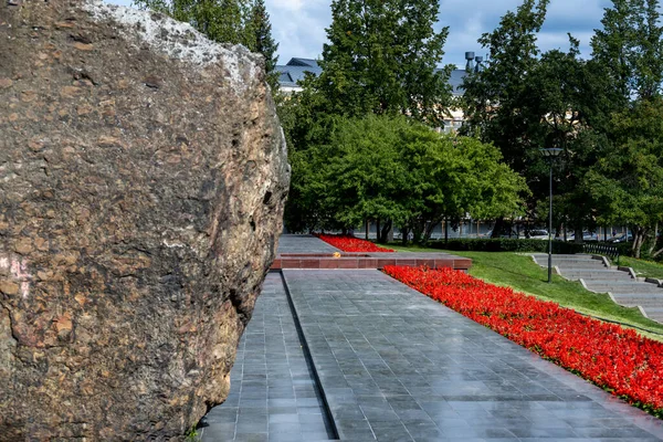 Parktaki Granit Taş Kırmızı Çiçeklerin Üzerinde — Stok fotoğraf