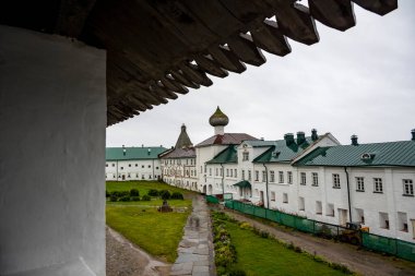 Yağmurlu bir gökyüzünün arka planında kuleleri ve iç binaları olan eski bir taş kale manastırı.