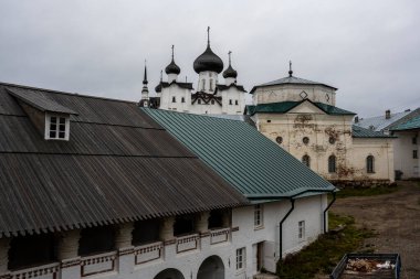 Yağmurlu bir gökyüzünün arka planında kuleleri ve iç binaları olan eski bir taş kale manastırı.