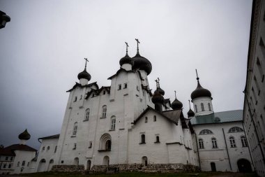 Yağmurlu bir gökyüzünün arka planında kuleleri ve iç binaları olan eski bir taş kale manastırı.