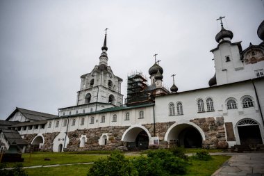 Yağmurlu bir gökyüzünün arka planında kuleleri ve iç binaları olan eski bir taş kale manastırı.