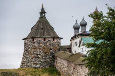 Yağmurlu bir gökyüzünün arka planında kuleleri ve iç binaları olan eski bir taş kale manastırı.
