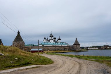 Yağmurlu bir gökyüzünün arka planında kuleleri ve iç binaları olan eski bir taş kale manastırı.