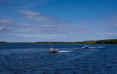 Adalar, sinyal yapıları ve hız teknesinden gelen gemilerle büyük bir göl manzarası.