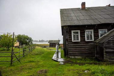Beyaz yağmurluklu bir kadın, kimsenin yaşamadığı bir adada manzaraya aşina olur.