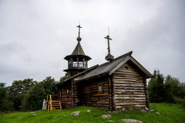 Beyaz yağmurluklu bir kadın, kimsenin yaşamadığı bir adada manzaraya aşina olur.