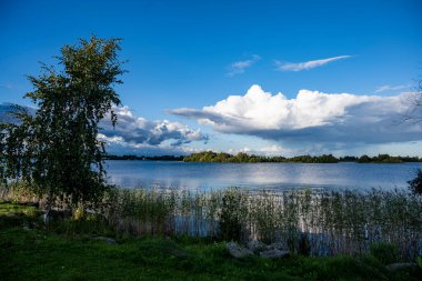Bulutların ve mavi gökyüzünün ardında büyük, güzel bir göl manzarası.