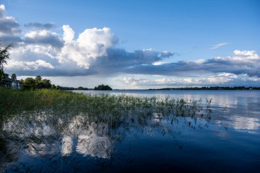 Bulutların ve mavi gökyüzünün ardında büyük, güzel bir göl manzarası.