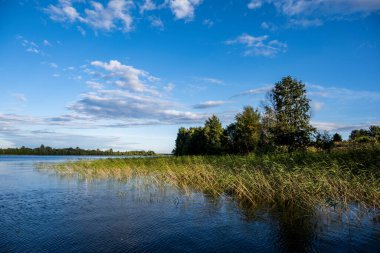 Bulutların ve mavi gökyüzünün ardında büyük, güzel bir göl manzarası.