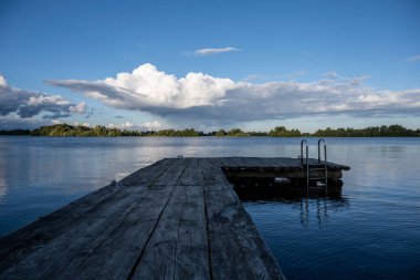 Bulutların ve mavi gökyüzünün ardında büyük, güzel bir göl manzarası.