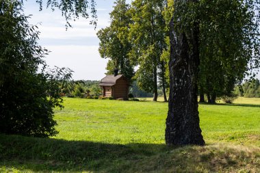 Kırsal alanlar yeşil tarlalar, ağaçlar ve açık alanlar bulutlu bir gökyüzüne karşı.