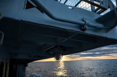 Batan güneşin su yüzeyindeki yansıması geminin bazı kısımlarının arka planına göre