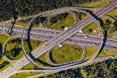 Arkaplanda insansız hava aracından çekilen şehirle karmaşık bir karşılıklı geçiş sistemine sahip bir yolun panoramik görüntüsü