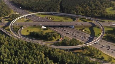 Hareket halindeki arabalarla, insansız hava aracının arka planından çekilen karmaşık bir kavşak sistemine sahip bir yolun panoramik görüntüsü.