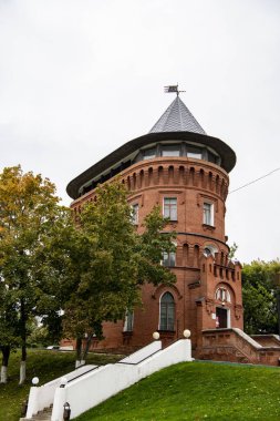 Ağaçların arasındaki parkta klasik kırmızı tuğlalı gözetleme kulesi.