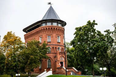 Ağaçların arasındaki parkta klasik kırmızı tuğlalı gözetleme kulesi.