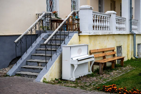 white piano near the stairs near a residential building on the street
