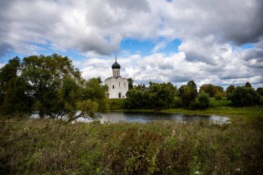 Fırtınalı bir gökyüzünün zeminine karşı yeşil çayır beyaz antik kilise manzarası