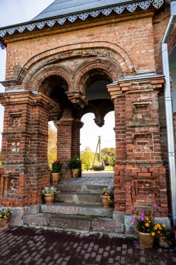 Ormanın yakınındaki bir tepede mavi gökyüzüne karşı eski bir kırmızı tuğla kilise.