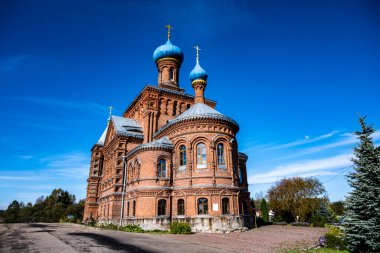 Ormanın yakınındaki bir tepede mavi gökyüzüne karşı eski bir kırmızı tuğla kilise.